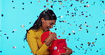 Confetti, gift and surprise with woman in studio for birthday, celebration and event. Happiness, present and party with female isolated on blue background for excited, notification and giveaway