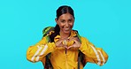 Heart, face and a woman with love for travel isolated on a blue background in studio. Happy, care and portrait of a traveling girl showing a gesture for enjoyment of tourism, backpacking and trekking