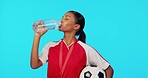 Woman athlete, drinking water and studio for sport, soccer training or healthy by blue background. Indian girl, young football player or drink from bottle for hydration, wellness or sports for health