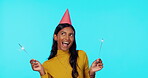 Portrait, party and sparklers with a woman on a blue background in studio for a birthday celebration. Happy, smile and hat with an attractive young female celebrating or partying at a social event