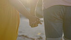 Back, couple and holding hands at beach for love, loyalty and flare at sunset. Closeup hand of man, woman and ocean for trust, support and vacation to travel, freedom and summer date for life partner