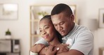 Love, happy and man hugging his girlfriend with care in the living room of the apartment. Happiness, romance and young African couple embracing and kissing for intimate moment together in their home.