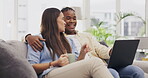 Laptop, coffee and couple talking in living room on home sofa, relax or online shopping. Computer, interracial and happiness of man and woman on couch internet browsing, social media or web scrolling