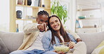 Couple, popcorn and watching tv in home, pointing and relaxing on sofa in living room. Face portrait, interracial and happy black man and woman streaming television, movie or film while eating food.