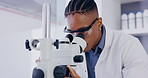 Science, microscope and innovation with a doctor man at work in a laboratory for research or breakthrough. Medical, sample and zoom with an african male scientist working in a lab for an experiment