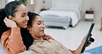 Lesbian, couple and women relax on couch with tablet, happy with online streaming service and watching a video or movie. Comfort, bonding and people spending time together at home with technology