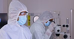 Covid, research and medical scientist working on a vaccine or analysis of a sample using a microscope in a hazmat suit. Computer, teamwork and science team doing an experiment in partnership in a lab