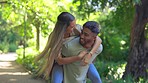 Love, nature and piggy back for happy couple walking in garden and bonding on summer weekend together. Interracial happiness, woman jumping on man with smile and laugh on fun, romantic date in park.