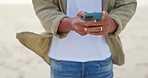 Hands typing on phone, man on beach and communication with technology on holiday travel. Nature, outdoor sea and person writing message, email or checking gps location on smartphone while on vacation