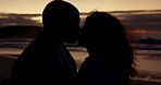 Kiss, silhouette and sunset with couple at beach for romance, bonding or affectionate. Happy, travel and summer vacation with man and woman kissing on date for holiday, care and honeymoon celebration