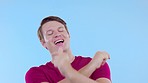 Happy, dance and young man in a studio while listening to music, playlist or album and moving. Happiness, smile and male model from Canada dancing to a song on the radio isolated by a blue background