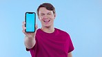 Face, mockup and man with smartphone, screen and smile against a blue studio background. Portrait, male and person with cellphone, happiness and mobile app for social media, space and confident guy
