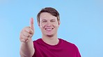 Face, support and man with thumbs up, smile and agreement against blue studio background. Portrait, male person or guy with symbol for solidarity, ok and like with gesture for well done and promotion