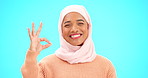 Muslim woman, ok sign and smile on face with hand for emoji, icon or agreement. Islamic female with hijab and symbol for thank you, support and agreement or approval on a studio blue background