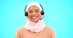 Call center, woman face and isolated on blue background for agent, consultant or muslim telemarketing support. Happy telecom, technical support or communication of hijab person with headset in studio