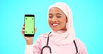 Green screen, phone and nurse isolated on blue background with medical mobile app, tracking marker and healthcare mockup. Happy islamic doctor or woman face with cellphone product placement in studio