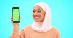 Muslim, phone or green screen and a woman on a blue background in studio holding a display with tracking markers. Islam, mobile contact and an attractive young female showing a screen for marketing