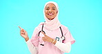 Woman doctor pointing to mockup isolated on blue background for healthcare presentation or product placement space. Happy face of nurse or medical muslim person show advertising mock up in studio