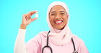 Nurse, healthcare and vaccine with a muslim woman on a blue background in studio for treatment. Medical, product and insurance with a young female medicine professional holding a glass bottle