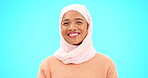 Muslim, wink and face of a woman with a smile, happiness and kindness. Islamic female with hijab and laughing for comic emoji or reaction to sale, mockup or funny meme on a studio blue background 