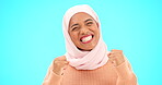 Muslim woman, happy celebration and excited about sale or advertising studio promotion. Islamic female fist, hand and hijab to celebrate bonus win, competition target or lottery on blue background 