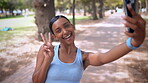 Selfie, fitness and happy woman in park for social media, workout goals and mobile app for training and peace sign. Indian sports person, influencer or runner in forest with workout profile picture