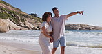 Pointing, love and holding hands with couple at beach for travel, relax and summer vacation. Happy, relationship and romance with man and woman on date for bonding, affectionate and commitment