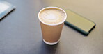 Coffee, latte art and takeaway with a disposable cup of caffeine on a desk in an office from above. Heart, drink and caffeine with a closeup beverage of a wooden table or surface at work for a break