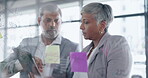 Business people, tablet and writing for schedule planning, brainstorming or collaboration on glass board at the office. Businessman and woman working with technology and sticky note for strategy