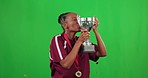Winner, black woman and trophy kiss on green screen in studio isolated on a background. Celebration medal, confetti and face portrait of person with happiness to celebrate winning, success and award.