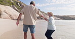 Senior couple, beach and holding hands while walking and happy on summer vacation or holiday. Old man and woman together at sea for love, care and fun or happiness outdoor for travel in retirement