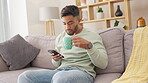 Relax, coffee and phone with a man on a sofa in the living room of his home thinking about the weekend. Mobile, contact and social media with a handsome young male drinking a beverage in the lounge