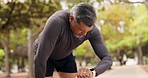 Fitness, watch and check of a mature man in a park rest after workout run and exercise. Outdoor, athlete and smartwatch of a person checking pulse, heart rate and run progress on a training app