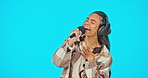 Woman singing, headphones and microphone isolated on blue background performance, voice or talent in recording studio. Face of singer, gen z musician or Influencer person at audition or concert event