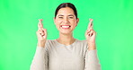 Excited woman, fingers crossed and face on green screen, background and studio for good luck. Portrait of happy female model hope for winning prize, wish and optimism with emoji sign, hands and smile