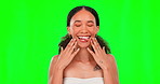 Portrait, beauty and funny face with a woman on a green screen background in studio for wellness. Luxury, relax and tongue with an attractive young female touching her soft, smooth or silky skin