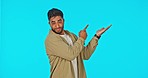 Face, pointing and man with hand space for mockup in studio isolated on a blue background. Confused, portrait and Indian person with product placement, marketing or advertising, doubt or decision.