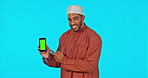 Green screen, phone and Islamic man showing chromakey on a cellphone feeling happy and isolated in a studio blue background. Muslim, excited and portrait of male approve and accept internet deal