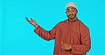 Pointing, face and muslim man in a studio with mockup space for product placement or advertising. Happy, smile and portrait of a islamic male model showing mock up for marketing by a blue background.