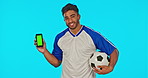 Green screen, phone and soccer player or man isolated on blue background for advertising on mobile app mockup. Indian football person or face of athlete in mock up, product placement space and studio