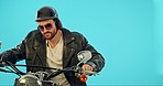 Sports, motorbike and man with a helmet in a studio before going for a ride for training. Fitness, adventure and punk male biker with sunglasses, leather jacket and bike isolated by a blue background