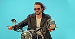 Fashion, motorbike and man in studio on blue background for road trip, adventure and leather aesthetic. Driving, motorcycle and man riding on mockup, edgy and confident, vintage and retro isolated