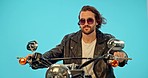 Motorbike, fashion and man relax in studio on blue background for road trip, drive and leather aesthetic. Driver, motorcycle and man on journey, vacation or riding, cool and retro, edgy and isolated