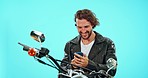 Success, happy and a biker with a phone for good news isolated on a blue background in a studio. Smile, excited and a man reading a winning email, chat or conversation on a mobile with a motorbike