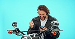 Motorbike, phone and man winning isolated on blue background success, bonus or online competition. Motorcycle person or winner fist pump reading news, travel promotion or sports achievement in studio