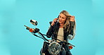 Happy, riding motorbike and a woman on a phone call isolated on a blue background in studio. Smile, talking and a young girl in conversation on a mobile while on a drive on a motorcycle for transport