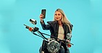 Selfie, blue background and woman on motorcycle smile on phone for adventure, road trip and holiday mockup. Motorbike, transport and happy girl take picture for social media, post or memory in studio