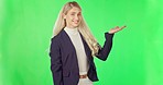 Business woman, pointing and product placement on green screen for advertising against a studio background. Portrait of happy or confident female showing hand in advertisement for marketing on mockup