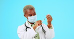 Covid, vaccine and a doctor black woman on a blue background in studio for healthcare or treatment. Medical, insurance and mask with a female medicine professional holding a syringe for injection