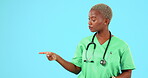 Serious face, black woman and doctor pointing, no and decision against blue studio background. Portrait, female employee and medical professional with gesture for space, choices and healthcare advice